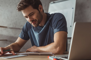 Selective focus of smiling designer planning mobile app with sketches and laptop on table © LIGHTFIELD STUDIOS