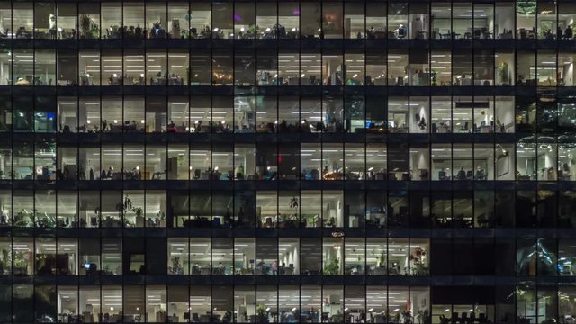 Panning to right view of office windows with working people