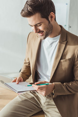 Smiling ux designer with notebook sketching user experience design in office