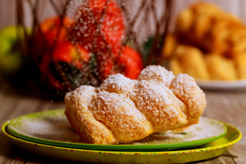 Powdered apple strudel on green plate with fresh apples.