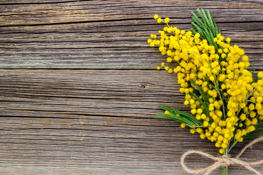 Yellow spring Mimosa bouquet with bow on a rustic wooden background with copyspace.