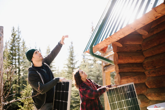 Couple installing solar panels on cabin