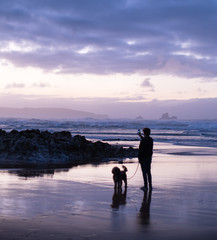 Hombre con perro saca foto en la playa. 