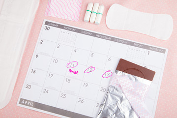 Period on calendar with chocolate and tampons 