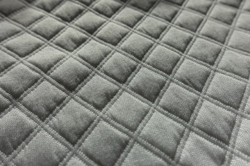 Closeup of white quilted fabric with diamonds pattern