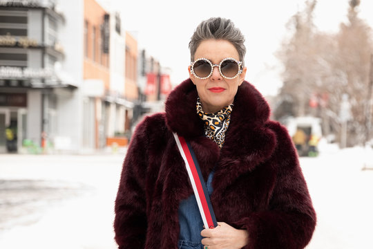 Portrait Confident, Stylish Woman In Fur Coat On Snowy Road