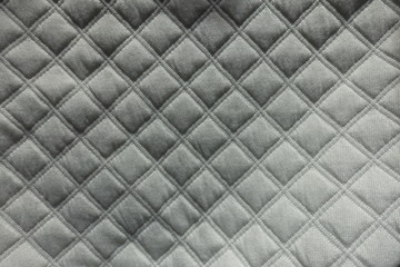 Top view of white quilted fabric with diamond pattern