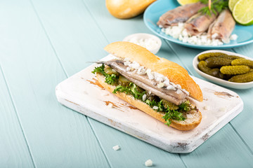 Traditional dutch snack, seafood sandwich with herring, onions and pickled cucumber. Broodje haring, copy space.