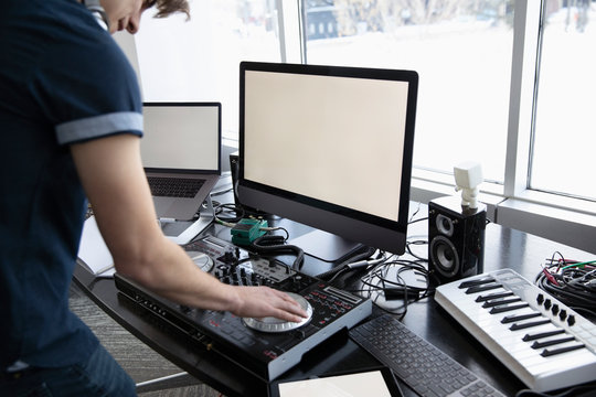 DJ Using Digital Mixing Tables At Desk