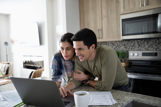 Couple using laptop in kitchen