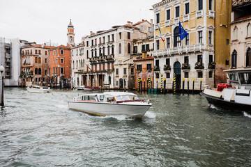 motor boats floating on canal near ancient buildings in Venice, Italy