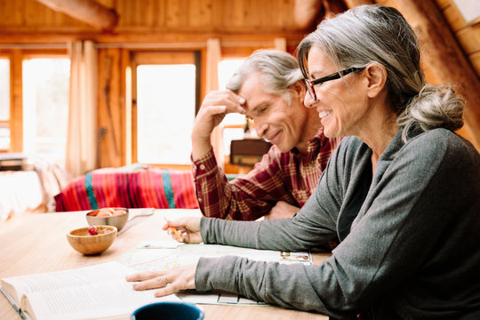 Mature Couple With Map At Cabin Table