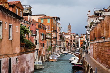 Fototapeta na wymiar bridge above canal, motor boats and ancient buildings in Venice, Italy
