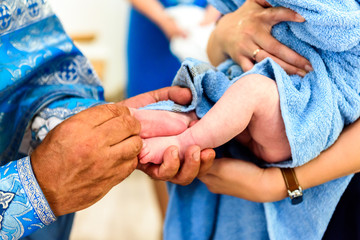 Christian rite of baptism of a child in a church, a priest anoints the world with the leg of a...