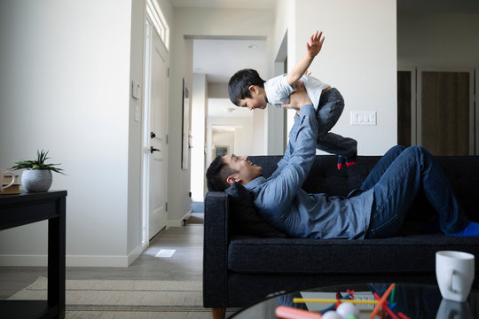 Smiling father playing with his son at home