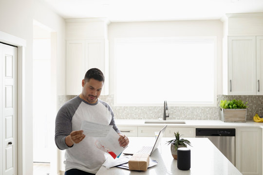 Man Paying Bills At Laptop In Kitchen