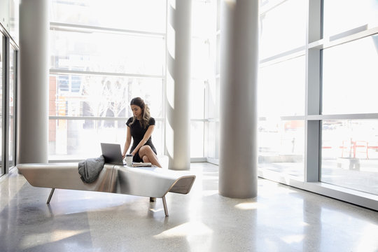 Businesswoman Working At Laptop In Office Lobby