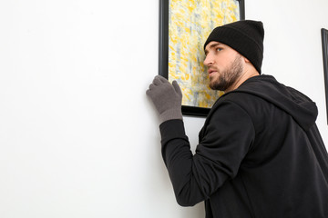 Thief stealing picture from art gallery