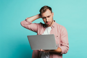 bearded pensive man using laptop, isolated on blue