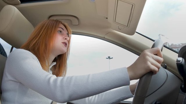 Pissed off displeased angry aggressive woman driving a car shouting at someone with hand fist up.