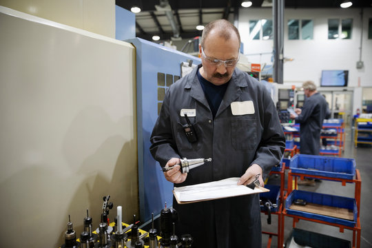 Male Machinist Examining Equipment In Factory