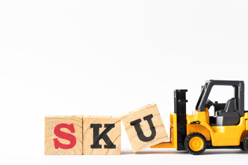 Toy forklift hold wood letter block U to complete word SKU (abbreviation of stock keeping unit) on white background