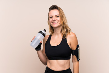 Blonde sport woman over isolated background with sports water bottle