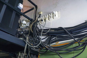 Lots of different cables hanging in a mess on the wall