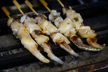 Seafood on wooden sticks on a grill in Osaka-Japan.