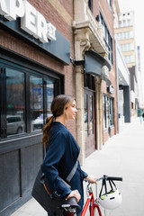 Businesswoman walking bicycle on urban sidewalk