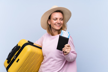 Blonde woman over isolated background in vacation with suitcase and passport