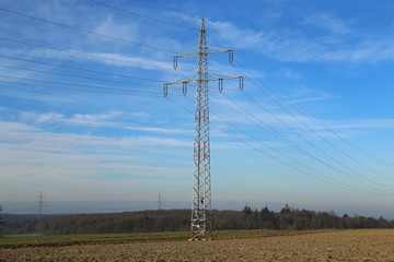 Landscape with electric pylons against the blue sky