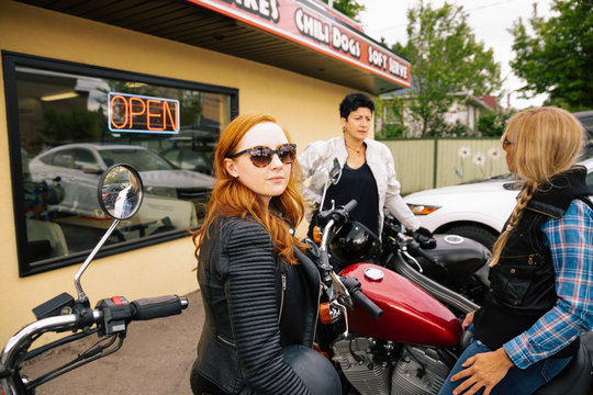 Portrait confident woman with friends on motorcycles outside drive-in