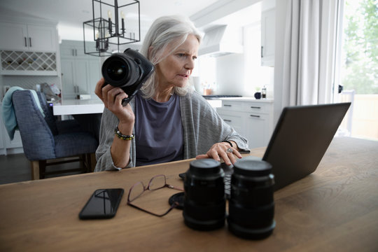 Senior woman with digital camera at laptop