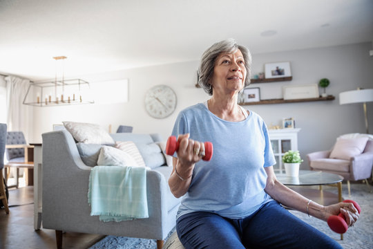 Senior woman exercising with dumbbells in living room