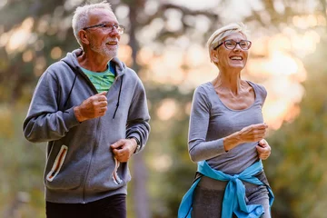 Rollo Fröhliches aktives Seniorenpaar, das im Park joggt. Trainieren Sie gemeinsam, um das Altern zu stoppen. © lordn