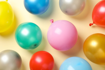 Multicolor balloons on beige background, top view