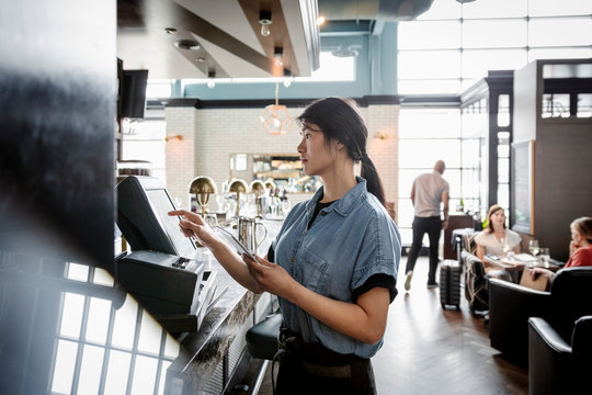 Waitress using touch screen computer in bar