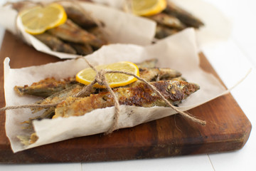 .Fried capelin with lemon on baking paper on a white backgroun