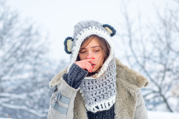 Obraz premium Cold flu winter season, runny nose. Showing sick woman sneezing at winter park.