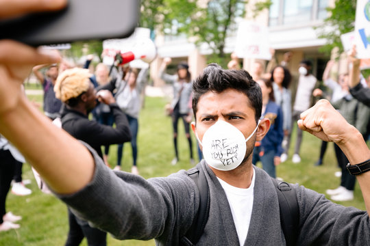 Student protester wearing pollution mask filming himself on smart phone