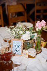 Beautiful floral arrangement of roses and greenery in glass vase on wedding table in restaurant, copy space. Rustic wedding decorations. Table setting