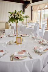 Table set with blank guest card, plate with pink and white serviette and cutlery on table, copy space. Place setting at wedding reception. Table served for wedding banquet in restaurant