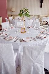 Table set with blank guest card, plate with pink and white serviette and cutlery on table, copy space. Place setting at wedding reception. Table served for wedding banquet in restaurant