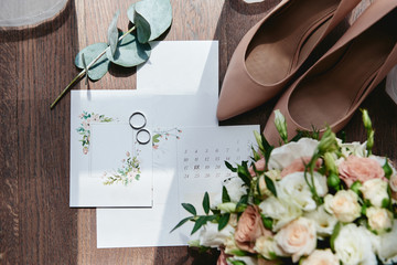 Luxury set of wedding invitations, wedding rings, elegant bride shoes on high heels on wood brown background. Honeymoon and wedding concept