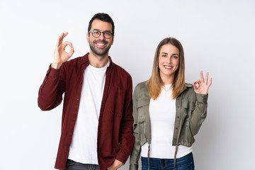 Couple in Valentine Day over isolated background showing an ok sign with fingers