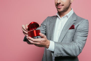 cropped view of man holding heart gift box for valentines day, isolated on pink