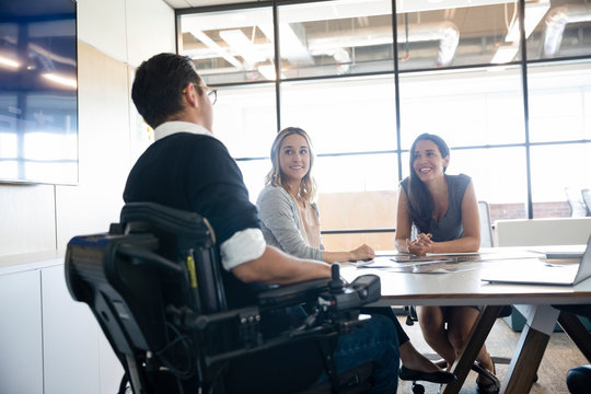 Businessman in wheelchair talking to female colleagues
