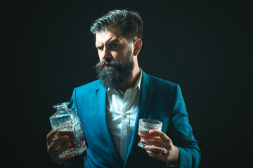 Man or businessman drinks whiskey on black background. Cheerful bearded man is drinking expensive...