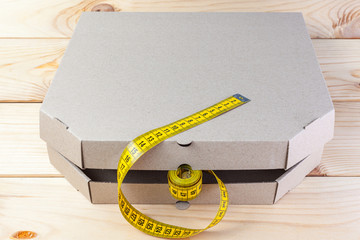 Yellow rag tape measure and pizza box . The concept of proper nutrition and weight loss.